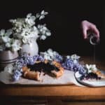 blueberry galette with woman pouring syrup over piece of galette