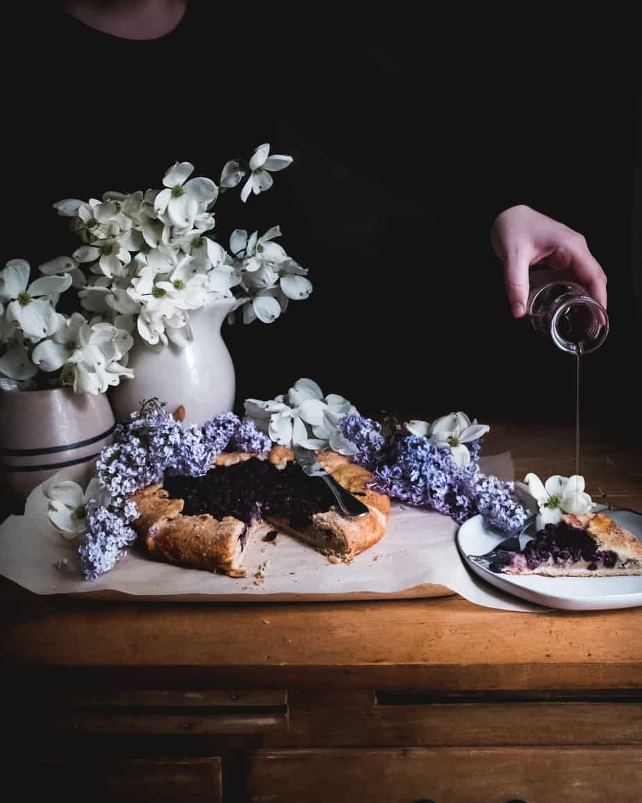 blueberry galette with woman pouring syrup over piece of galette