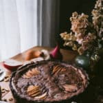 photo of chocolate tart with fruit and flowers next to window