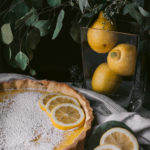 citrus dessert (lemon tart) on table with pitcher of lemons