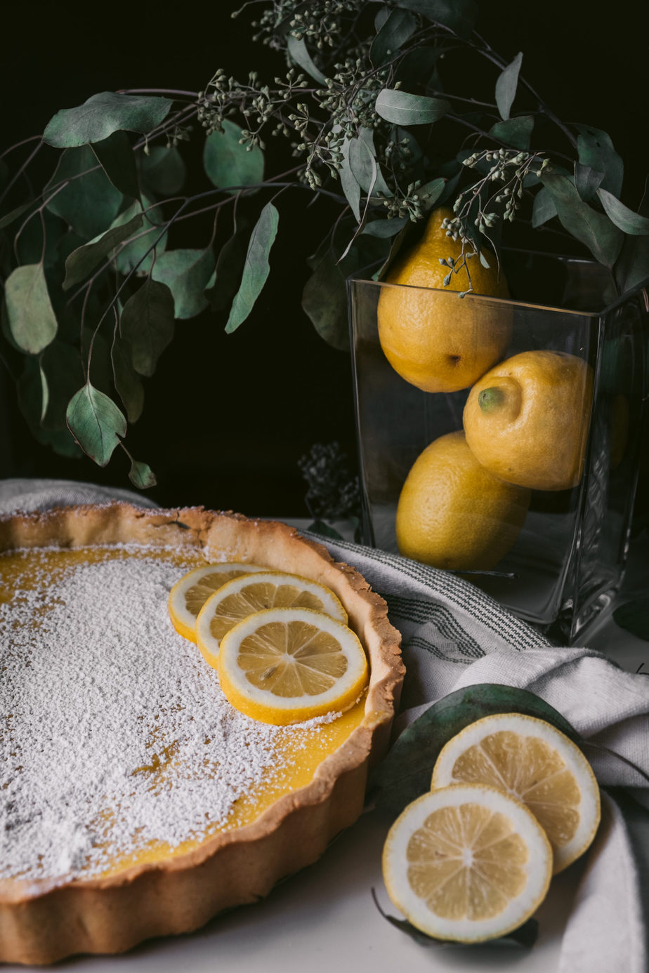 citrus dessert (lemon tart) on table with pitcher of lemons