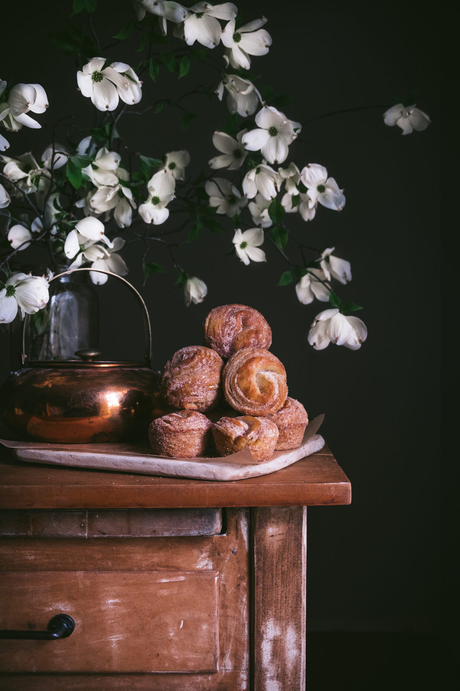 cinnamon sugar cruffins on a table next to dogwood flowers