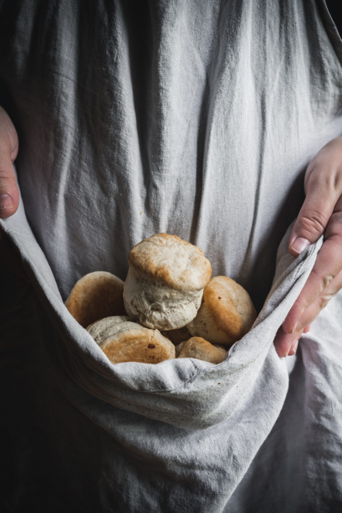 woman holding baking powder biscuits in apron