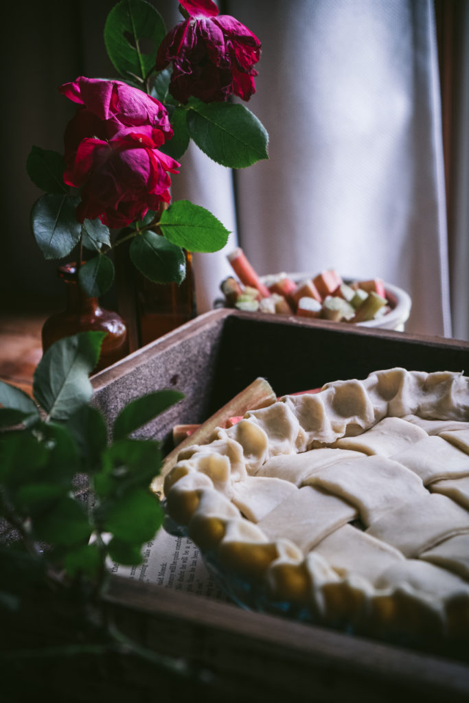 pie in a tray in front a window next to roses