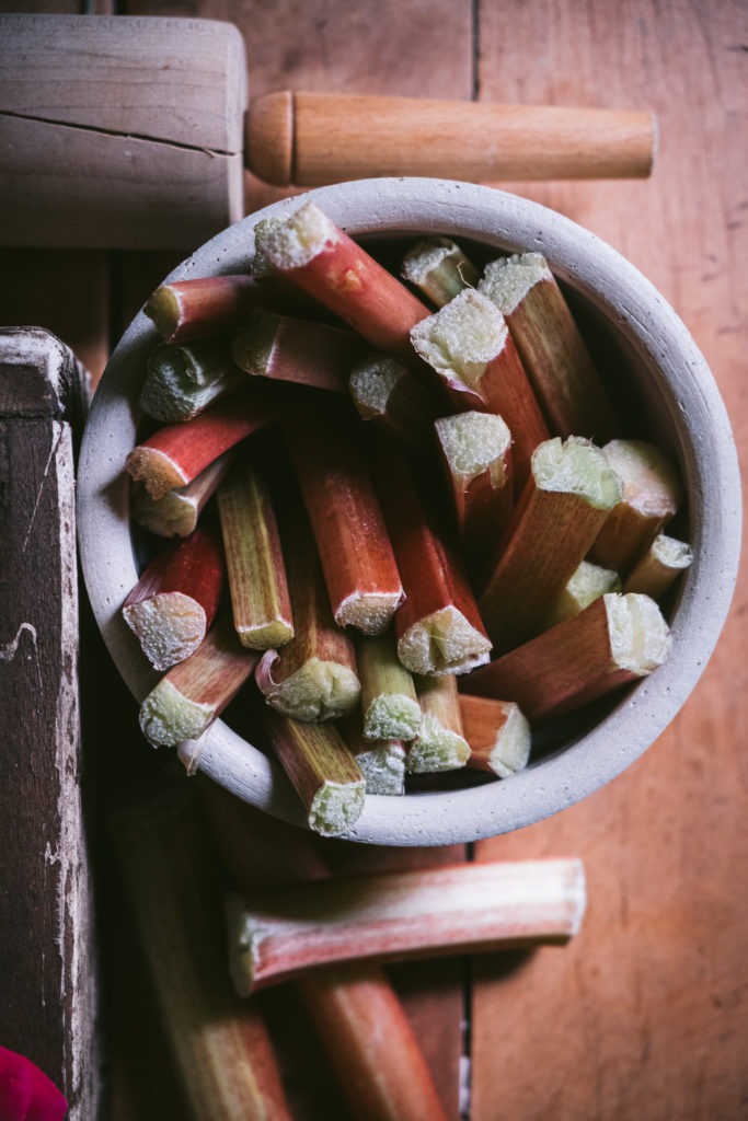 flatlay of rhubarb pieces in a bowl next to a rolling pin